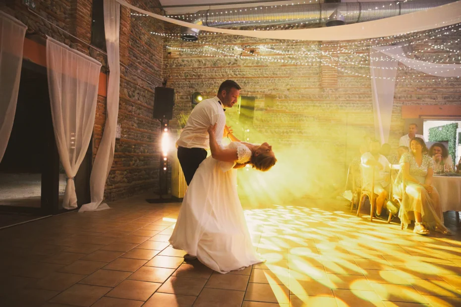 La soirée du mariage débute. C'est l'heure première danse. Les mariés dansent sur le dancefloor avec les lumières du DJ derrière eux. Les invités les regardent se déhancher dans la salle de réception du domaine.