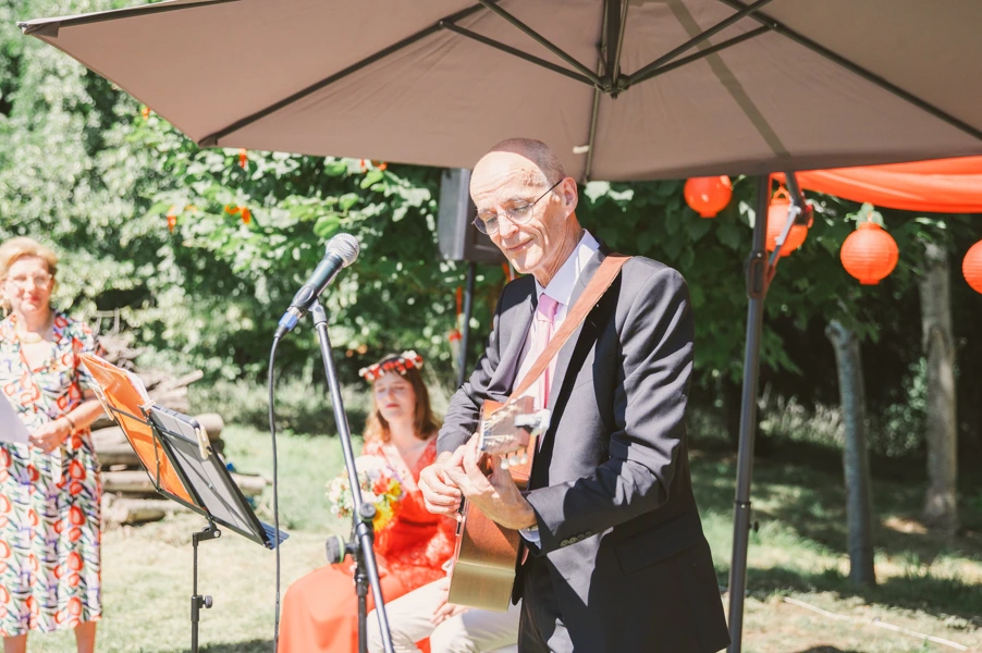 Le père du marié joue un morceau à la guitare après son discours pendant la cérémonie du mariage de son fils.