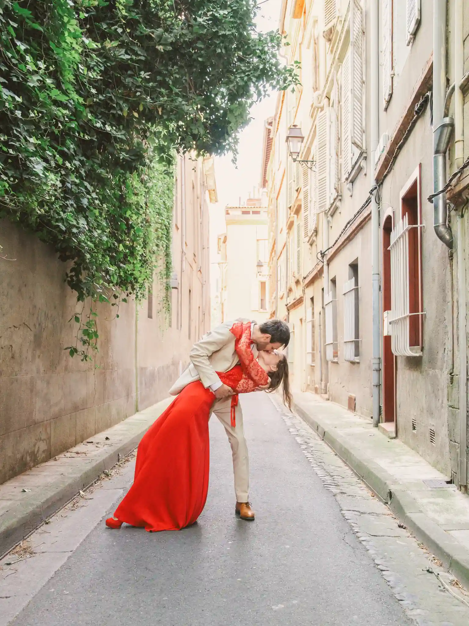 Photographe mariage Toulouse avec une séance couple jeunes mariés dans les rues de Toulouse. Au milieu d'une petite rue toulousaine, les mariés s'embrassent. Le marié fait basculé sa femme en arrière en l'embrassant