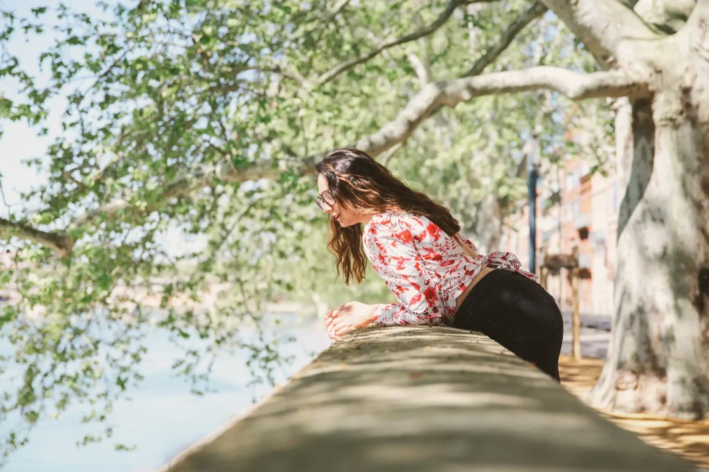Séance portrait à Toulouse sur les quais de Garonne avec Léa. Sous les platanes des bords de Garonne, Léa se penche pardessus le muret pour voir l'eau couler et les gens qui marchent au bord de l'eau.
