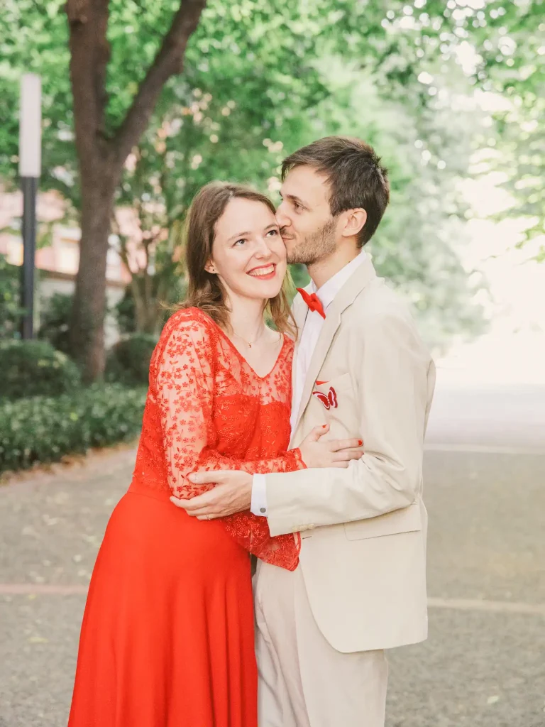 Photographe mariage Toulouse pour la Day After d'Auriane et Victor au jardin des plantes. Le couple s'enlace devant le muséum. Le mari embrasse sa femme sur le front.