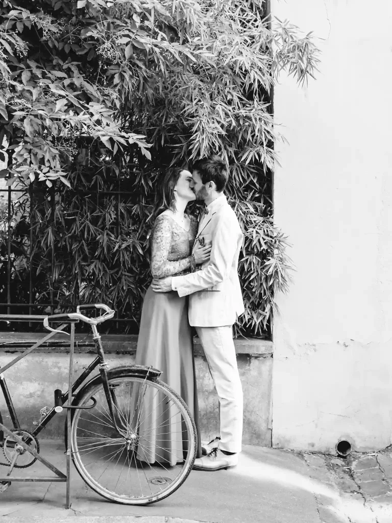 Photographe de mariage à Toulouse pour la day after d'Auriane et Victor qui s'embrassent derrière un vieux vélo attaché à une barrière