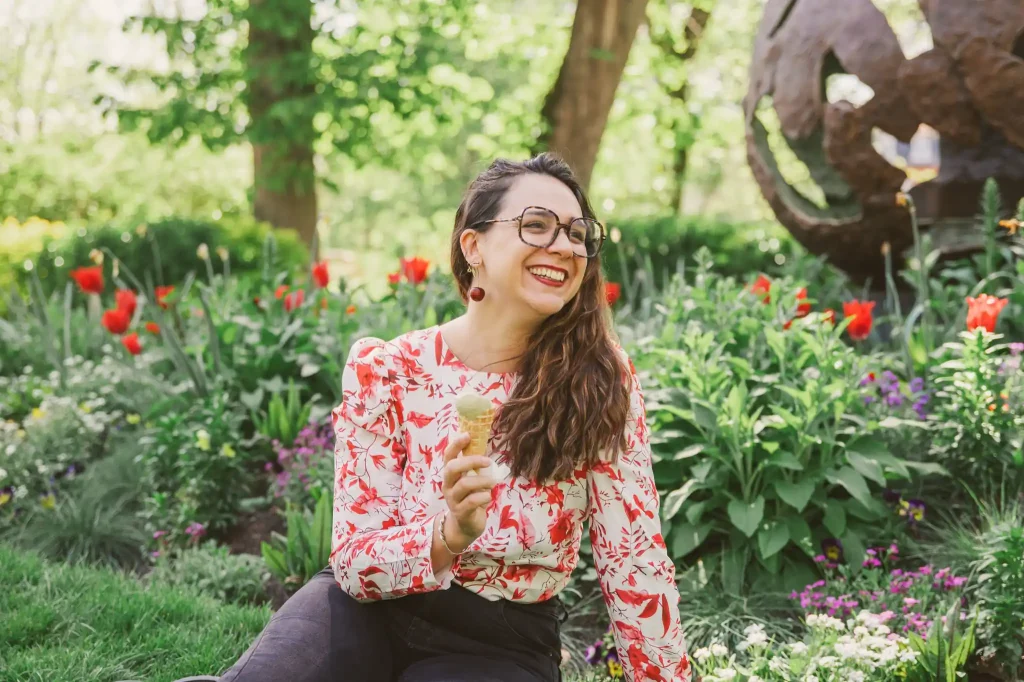 Séance photo portrait à Toulouse, au jardin des plantes avec Léa. Assise dans l'herbe elle rit aux éclats devant le statue du petit prince
