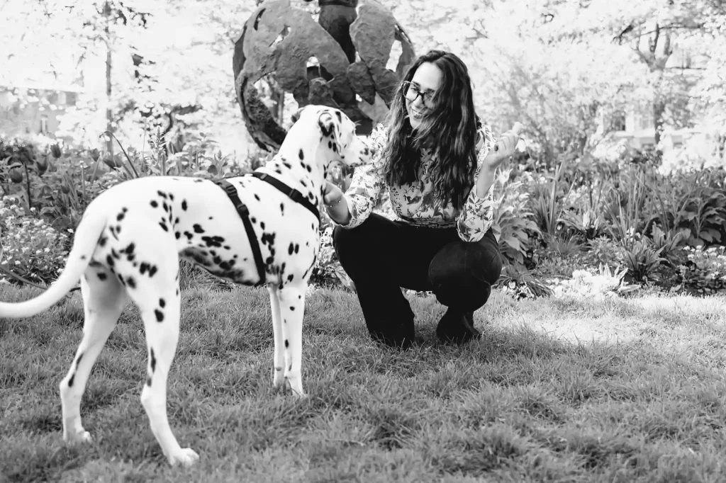 Séance photo portrait à Toulouse, au Jardin Royal avec Léa qui caresse un Dalmatien venu la voir. Elle le regarde, accroupi pour plonger ses yeux dans les siens 