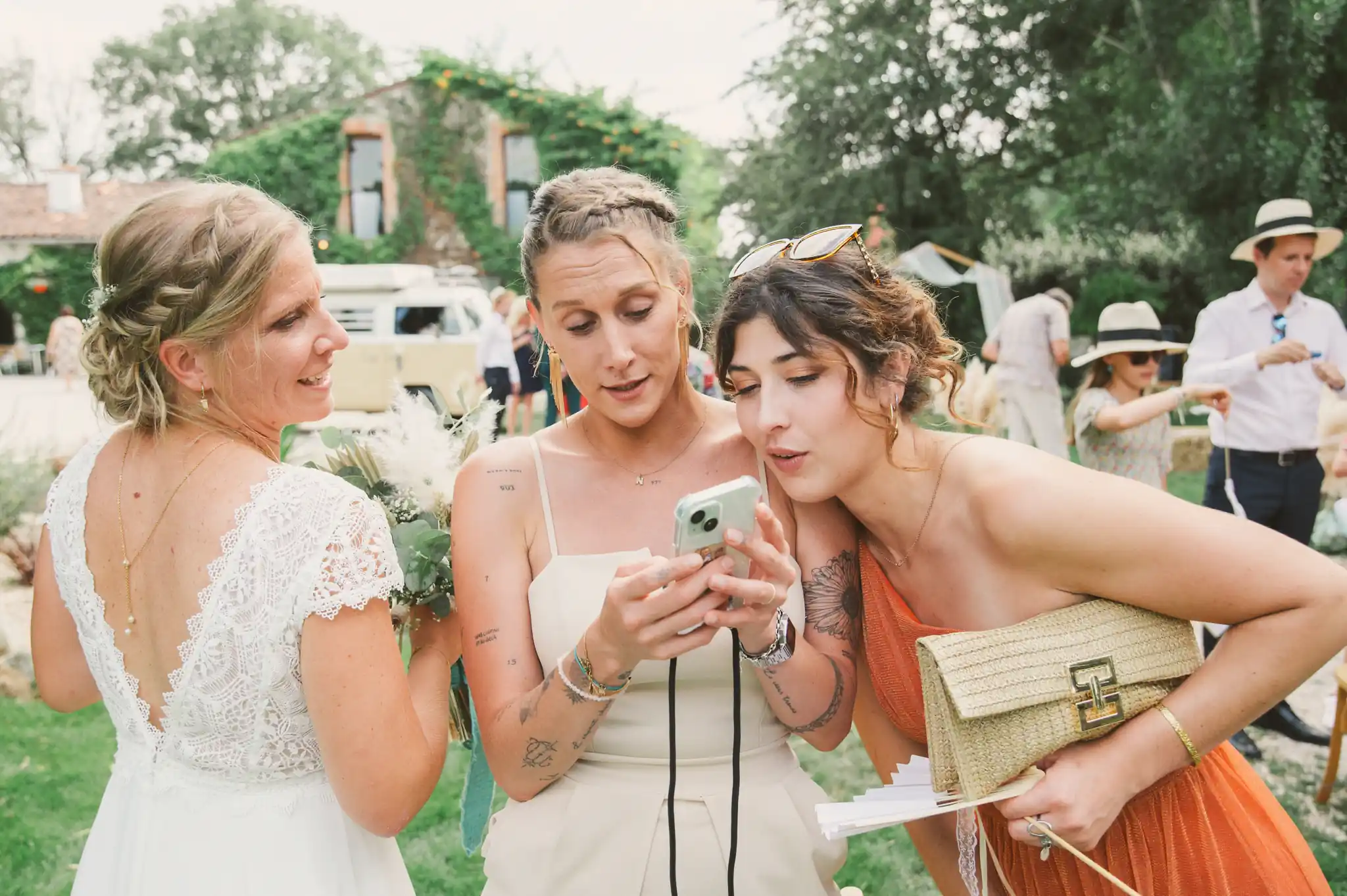 Photographe de mariage à Toulouse, au domaine de Courrèges, deux invités montrent leurs photos à la mariée