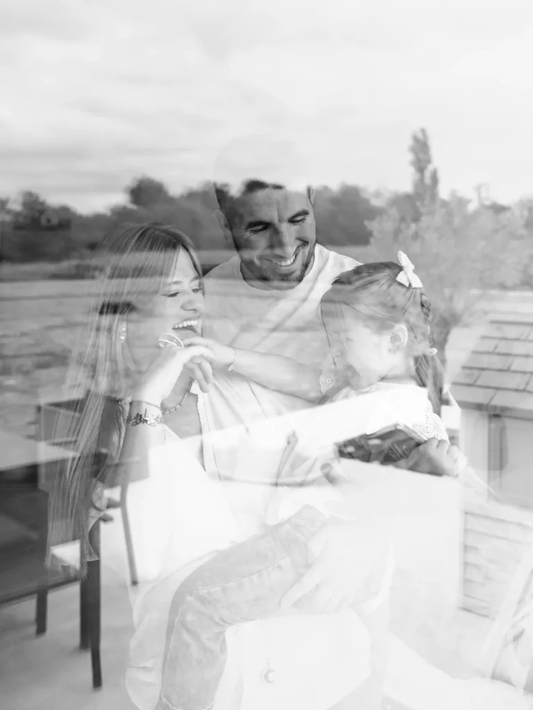Séance photo famille à Toulouse avec une famille qui s'enlace et rit aux éclat en jouant avec leur fille.
