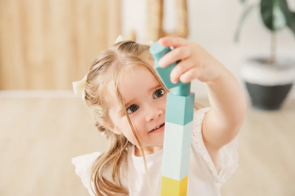 Séance photo famille à Toulouse avec une fille concentrée à construire une tour en kapla.