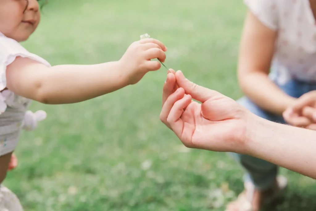 Séance photo famille à Toulouse au jardin des plantes. Le père offre une fleur à sa fille