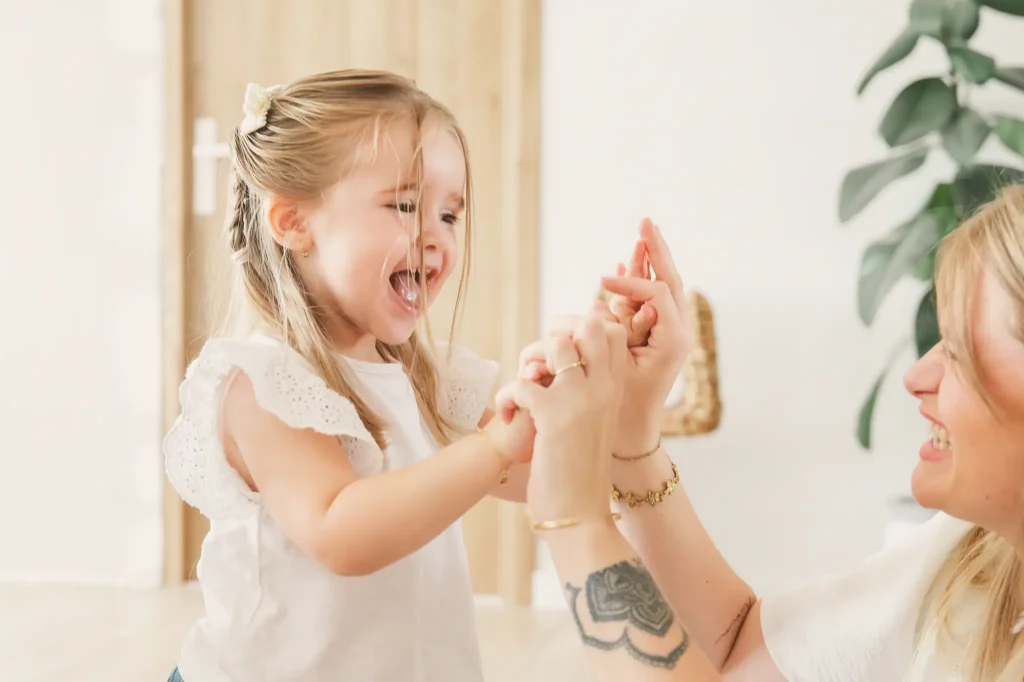 Séance photo famille à Toulouse, la maman tape dans les mains de sa fille pour la féliciter.
