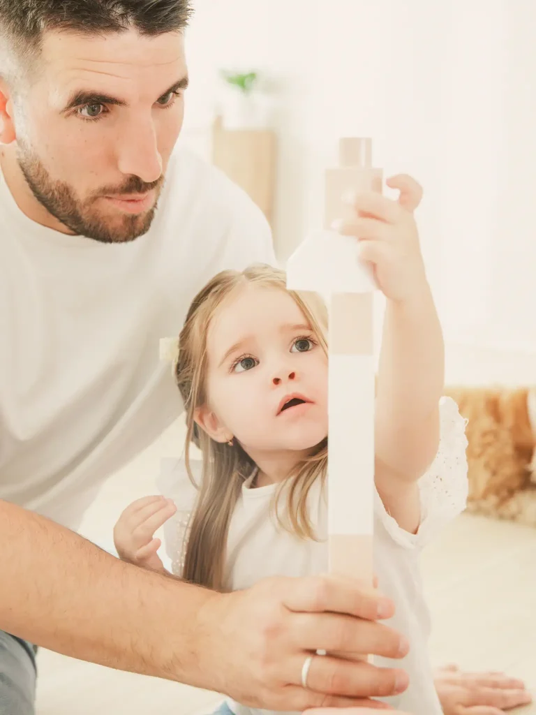 Séance photo famille à Toulouse, le père aide sa fille dans la construction d'une tour.