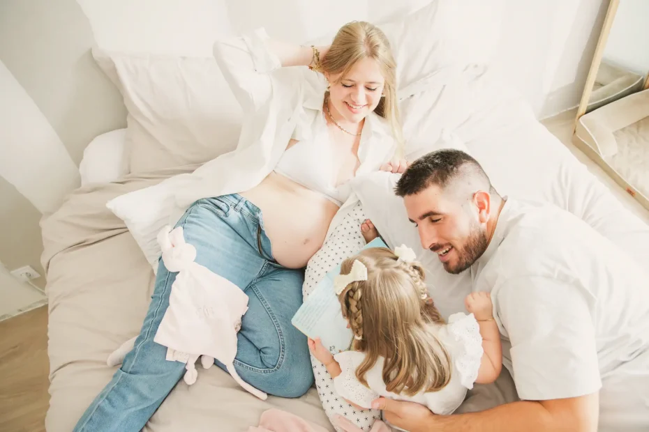 Séance photo grossesse à Toulouse. La famille allongée sur le lit, vue du dessus