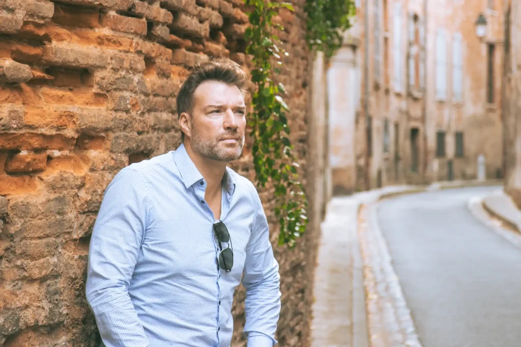Séance photo portrait à Toulouse dans le quartier des Carmes. Adossé contre un mur en brique, il regarde au loin.
