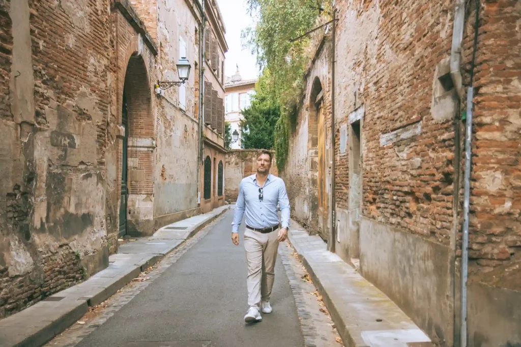 Séance photo portrait à Toulouse, il marche dans les ruelles étroites du quartier des Carmes