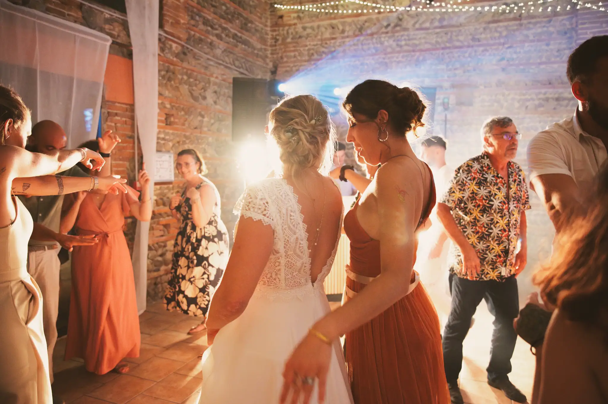 Photographe de mariage à Toulouse au domaine de Courrèges avec la mariée qui danse avec sa demoiselle d'honneur pendant la soirée.