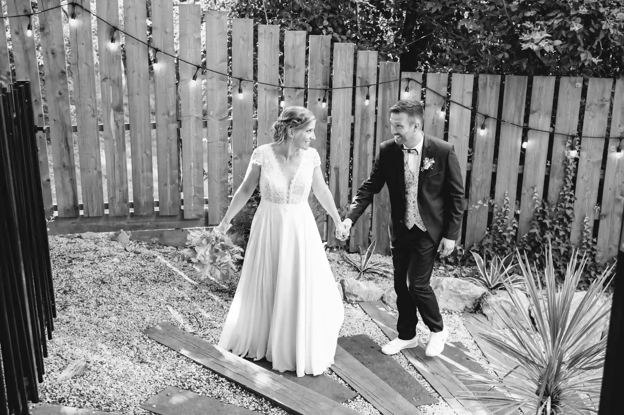 Photographe de mariage à Toulouse au domaine de Courrèges pendant les photos de couple. Les mariés montent les marches en se donnant la main.