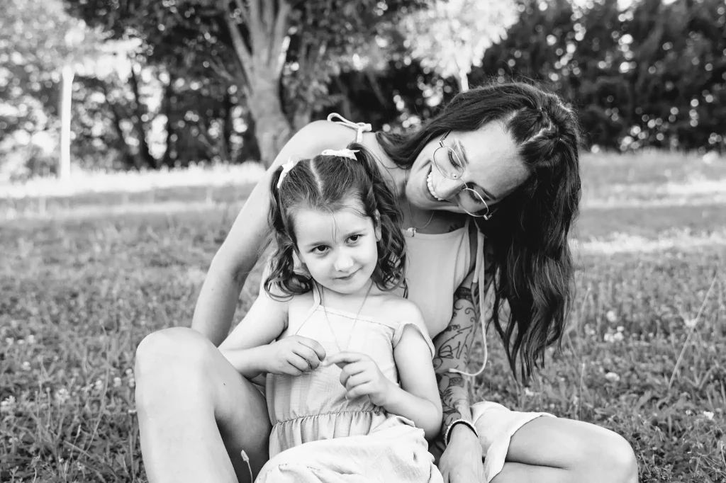 Séance photo famille à Toulouse avec la mère et sa fille qui discutent assises dans l'herbe de la base de loisir de Bruguières