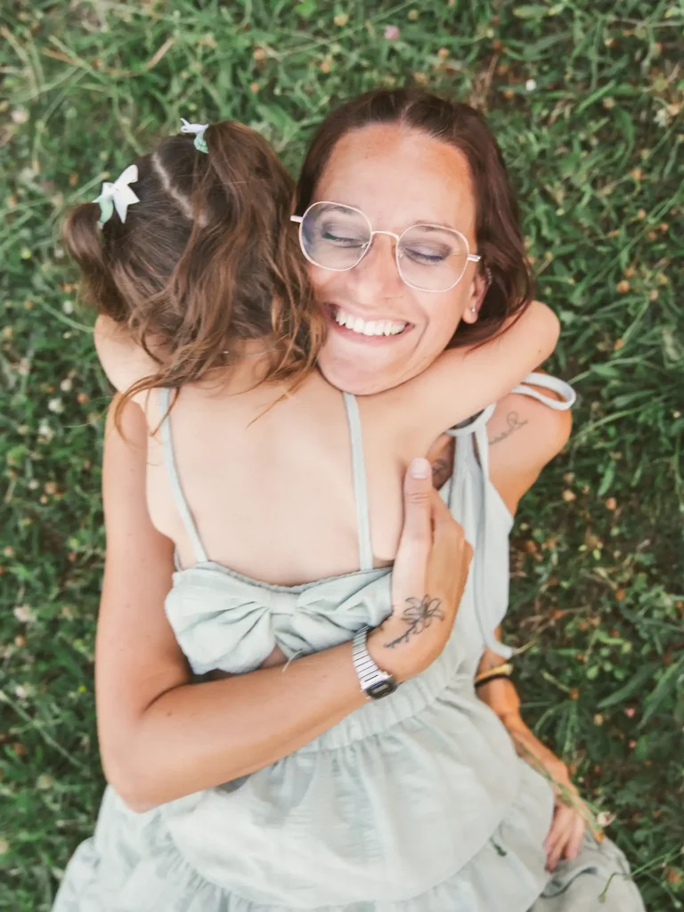 Séance photo famille à Toulouse avec la mère et sa fille qui se font un câlin dans l'herbe de la base de loisir de Bruguières