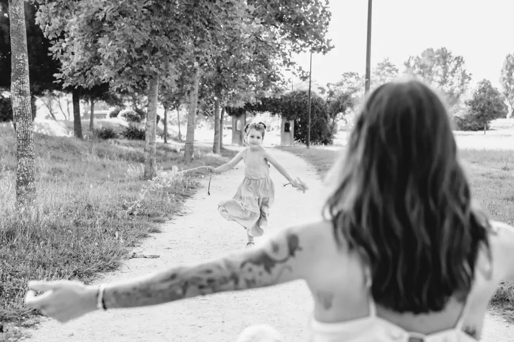 Séance photo famille à Toulouse avec une fille qui court dans les bras de sa mère agenouillée à quelques mètres
