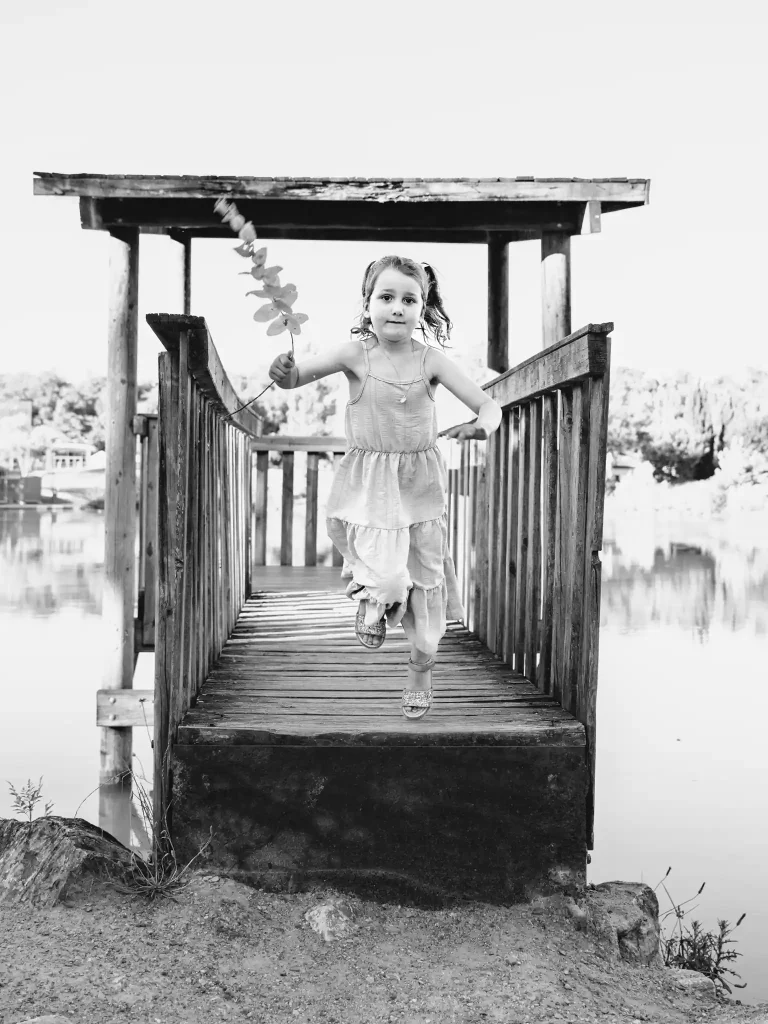 Séance photo famille à Toulouse avec une petite fille qui saute du ponton de la base de loisir de Bruguières