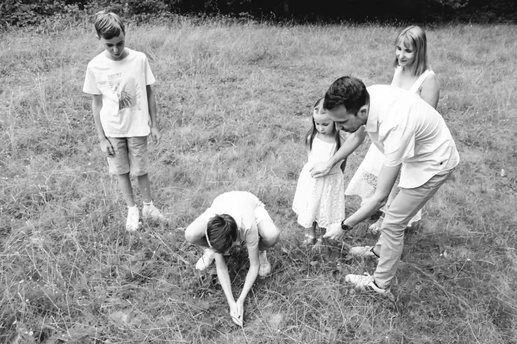 Séance photo famille à Toulouse dans la Forêt de Bouconne avec des enfants qui essaient d'attraper des papillons 