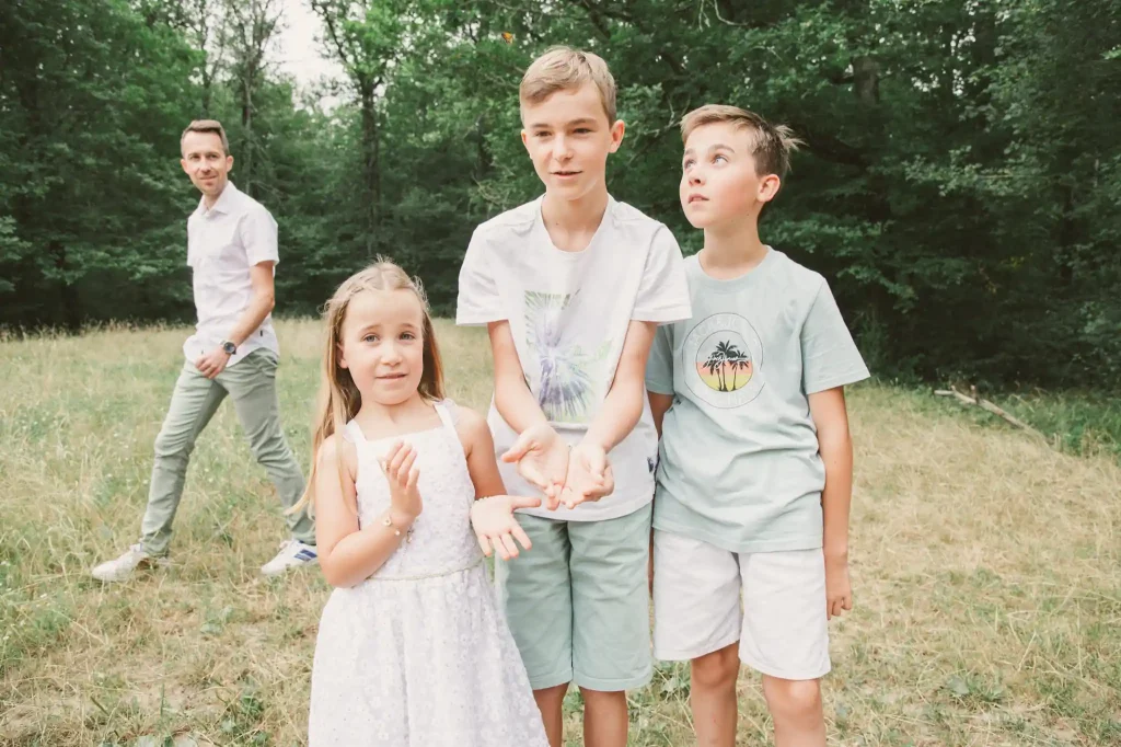Séance photo famille à Toulouse dans la Forêt de Bouconne avec des enfants qui jouent à observer des papillons pour les relâcher ensuite