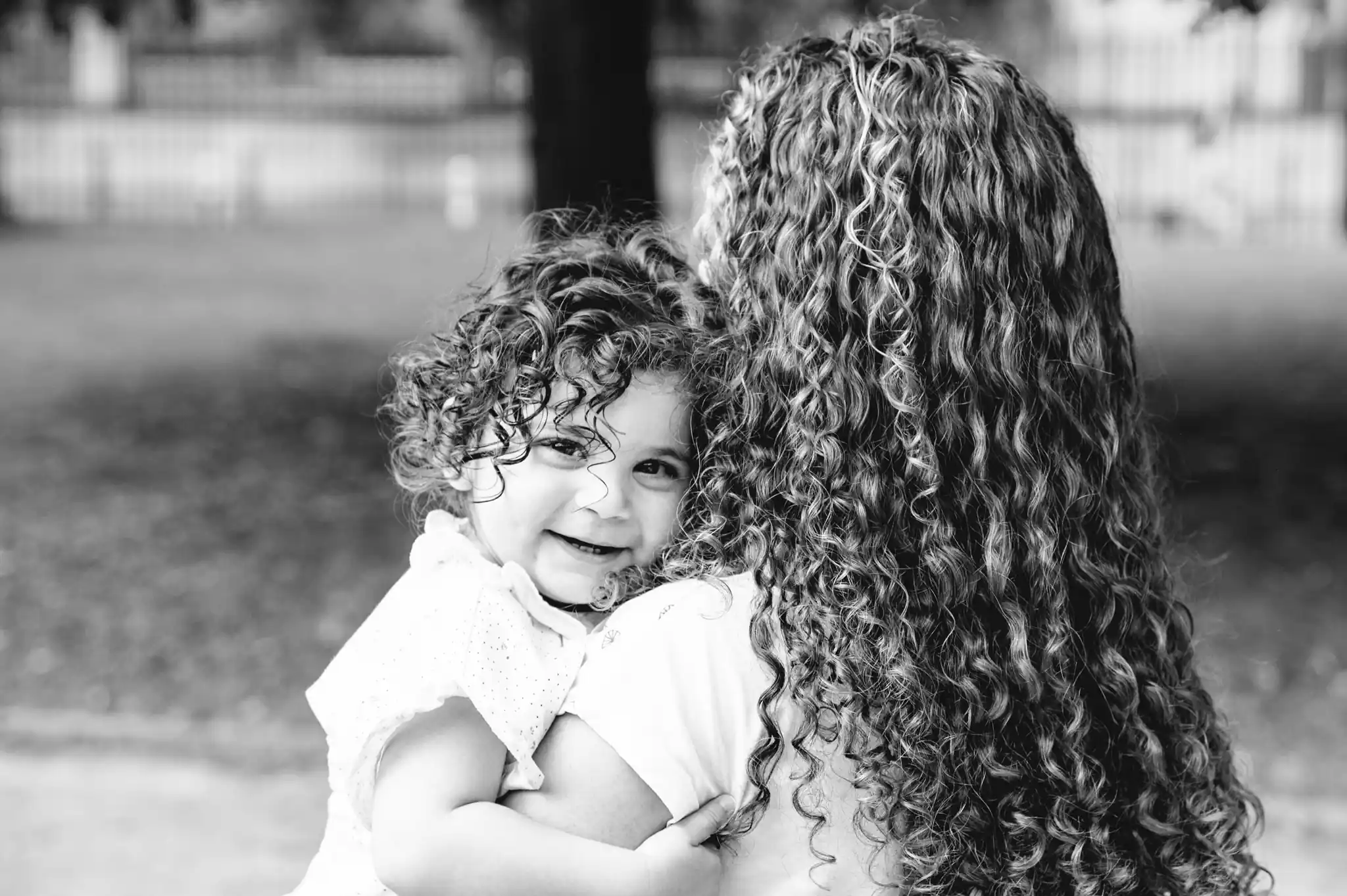 Séance photo famille à Toulouse, au jardin des plantes, avec la fille dans les bras de sa mère qui marche