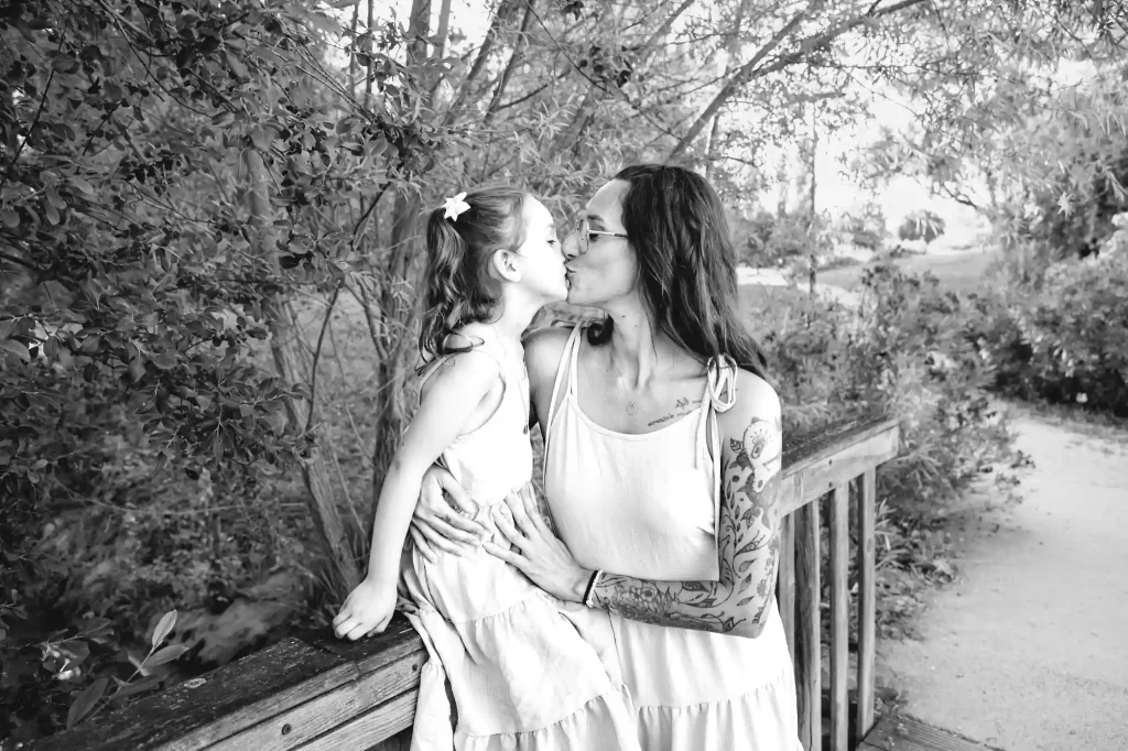 Séance photo famille à Toulouse avec mère et fille qui s'embrassent sur un pont n bois