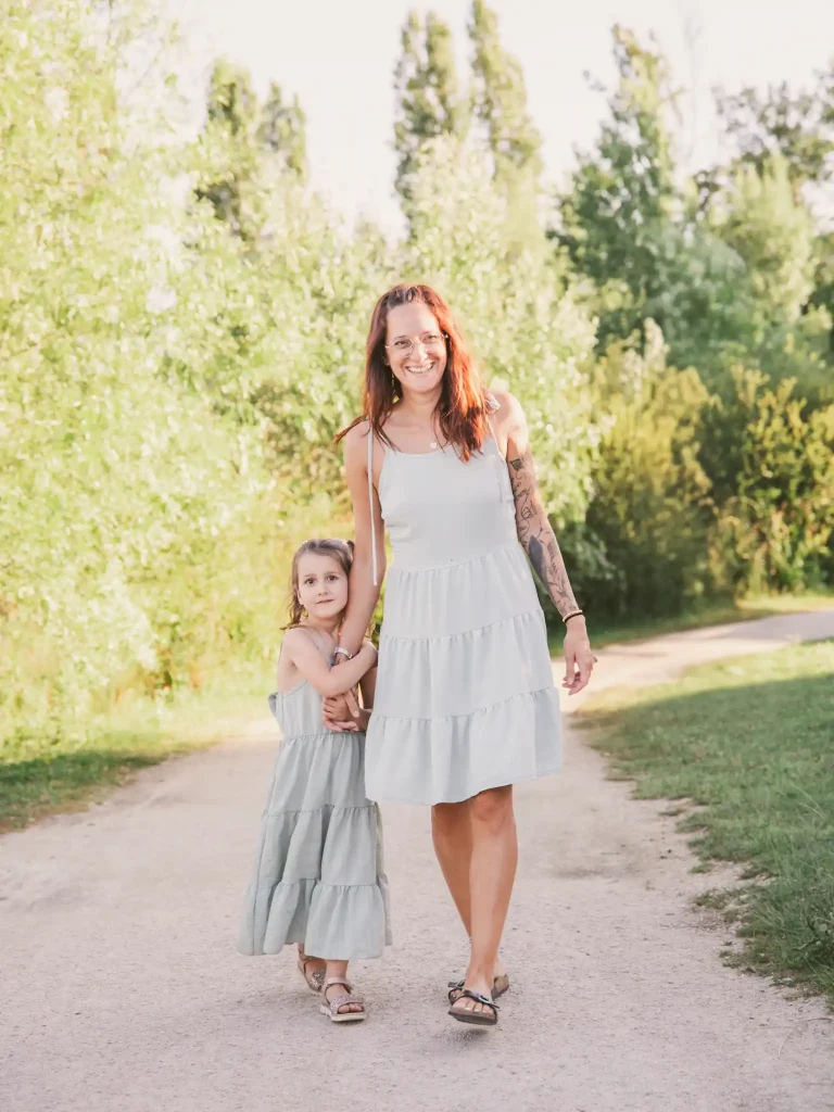 Séance photo famille à Toulouse : mère et fille marchent en se tenant la main sur le chemin de la base de loisir de Bruguières.