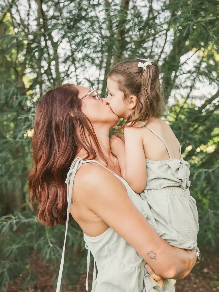 Séance photo famille à Toulouse avec la mère qui tient sa fille dans les bras et l'embrasse