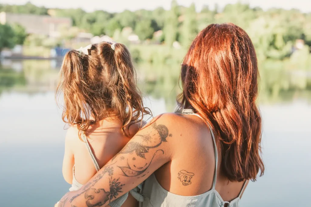 Séance photo famille à Toulouse, la mère et sa fille se prennent dans les bras pour regarder le lac de la base de loisir de Bruguières