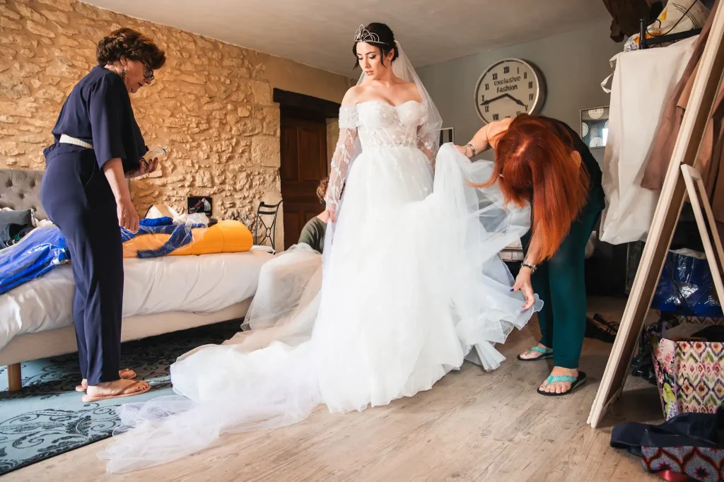 La mère et belle mère de la mariée l'aide à faire les derniers ajustements sur sa robe de mariée.