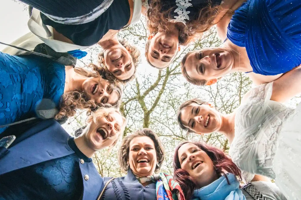 Les invitées proches de la mariée se mettent en cercle au dessus du photographe de mariage puis se mettent à crier pour l'encourager