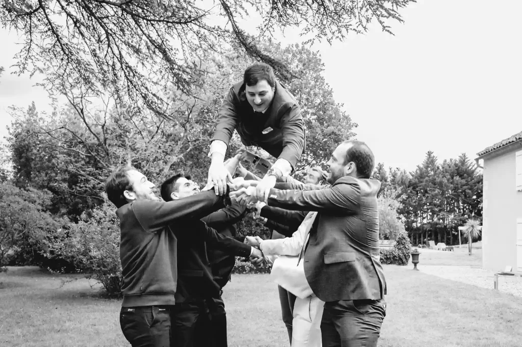 Les invités et témoins lancent le marié en l'air pendant le cocktail du mariage