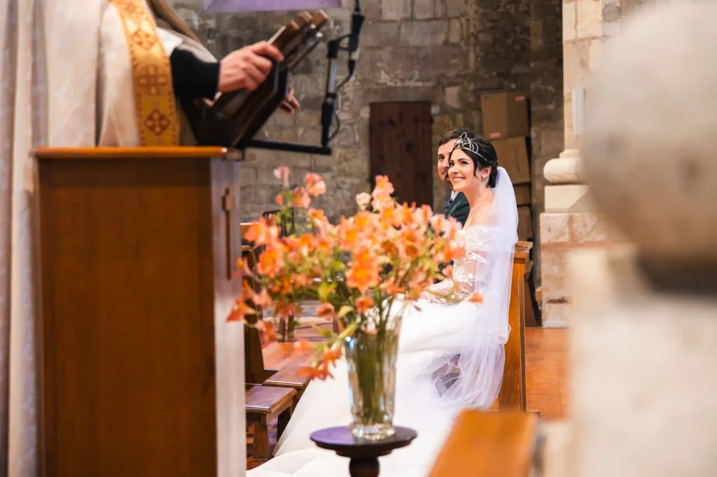 La mariée regarde l'officiant en souriant pendant la cérémonie religieuse.
