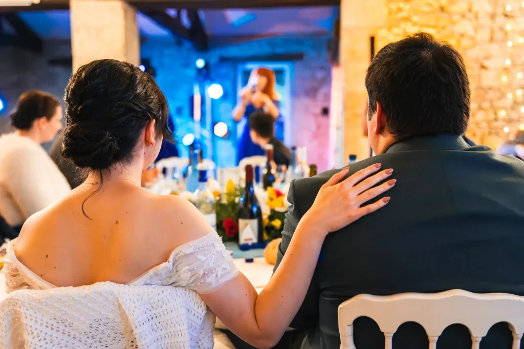 La mariée pose sa main sur l'épaule de son mari pendant le discours de ses parents