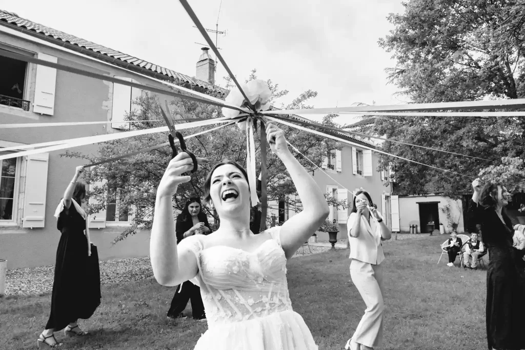 La mariée coupe les rubans avec des ciseaux pas très bien aiguisés et éclate de rire.