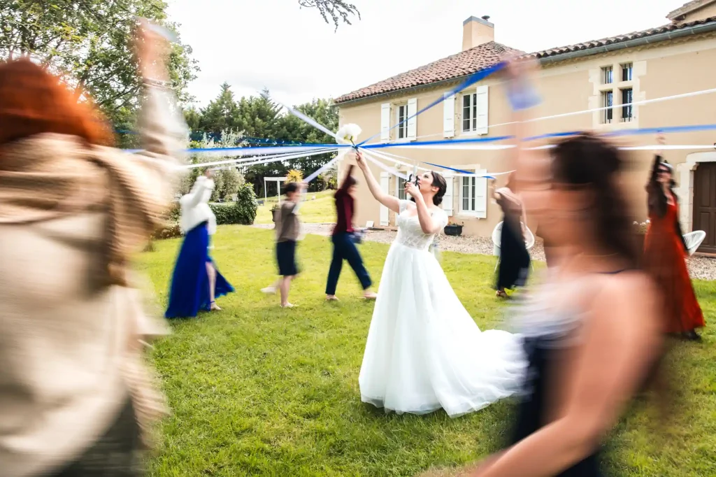 La mariée coupe les rubans que tiennent les invitées célibataires pendant qu'elles tournent autour d'elle pour cette animation renversante