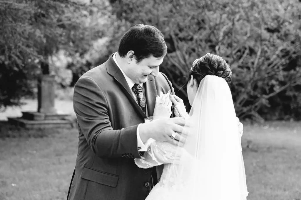 La mariée remarque les petits accessoires et les détails du costume de mariage de son fiancé lors de la séance photo du first look.