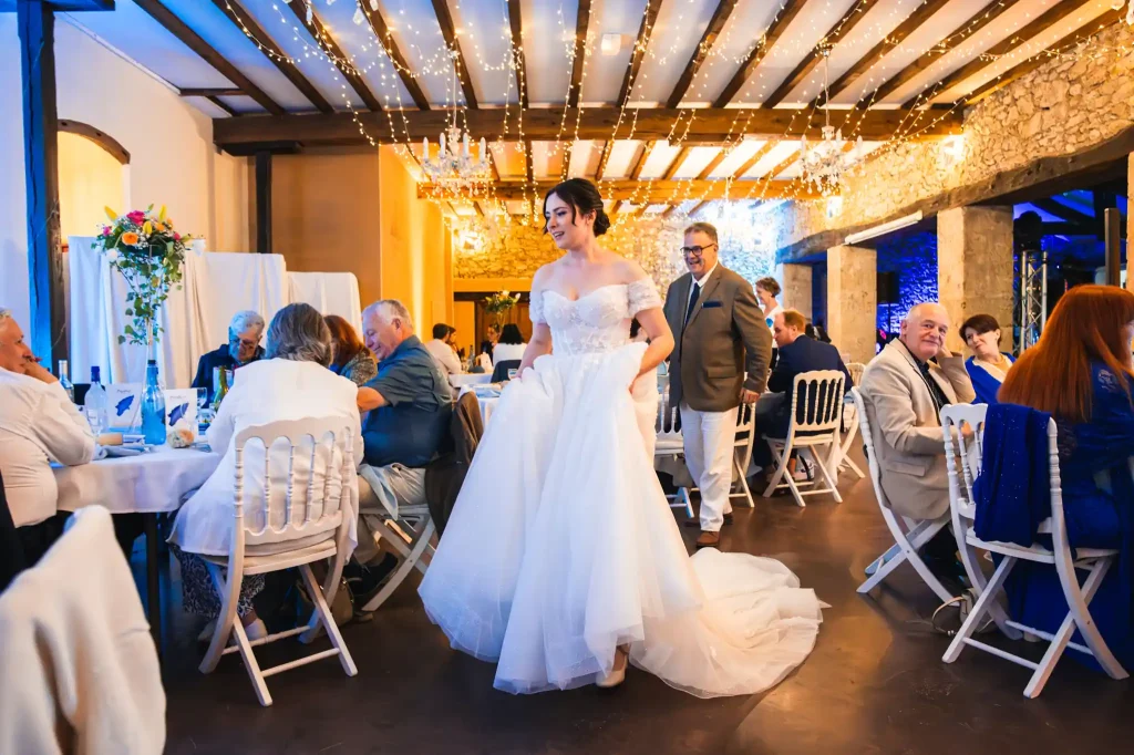 La mariée se déplace de table en table pour remercier chaque invités entre les différents plats du repas de mariage.