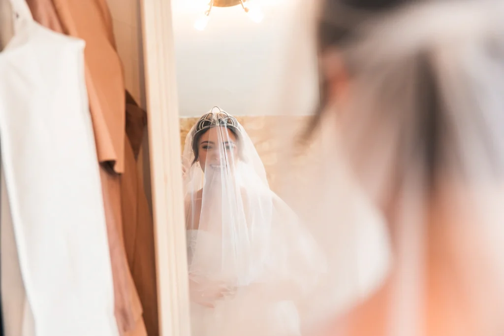 La mariée se redécouvre dans un miroir de la chartreuse de Dane. Les larmes sont au bord des yeux en se voyant avec son voile et son diadème sur la tête.