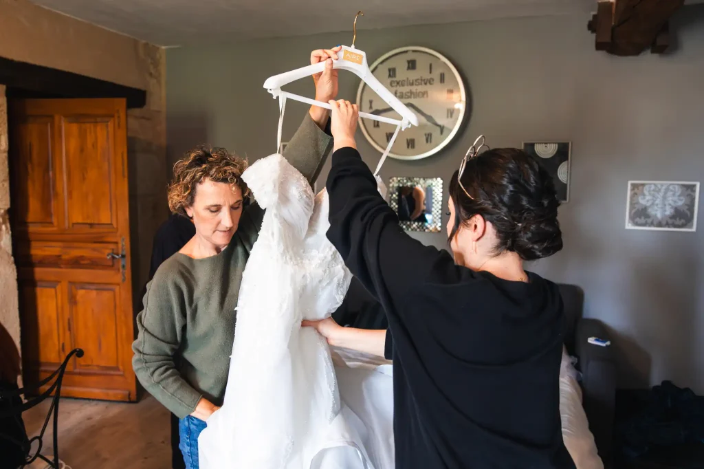 La mère et sa fille sortent la robe de mariage de sa housse avant de l'enfiler pour son mariage.