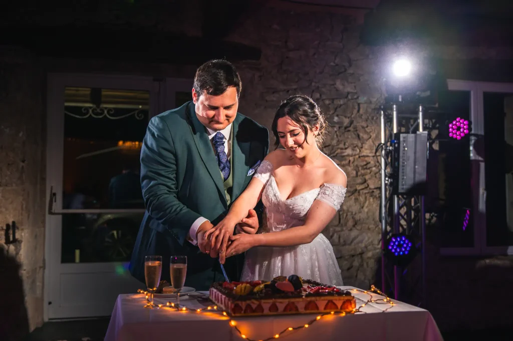 Les mariés découpent le gâteau de mariage en tenant le couteau à quatre mains