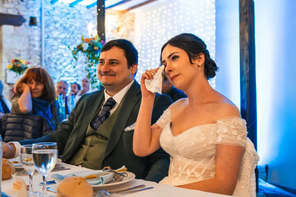 La mariée, émue du discours de ses témoins pendant le repas de mariage, essuie une larme de sa joue avec un mouchoir