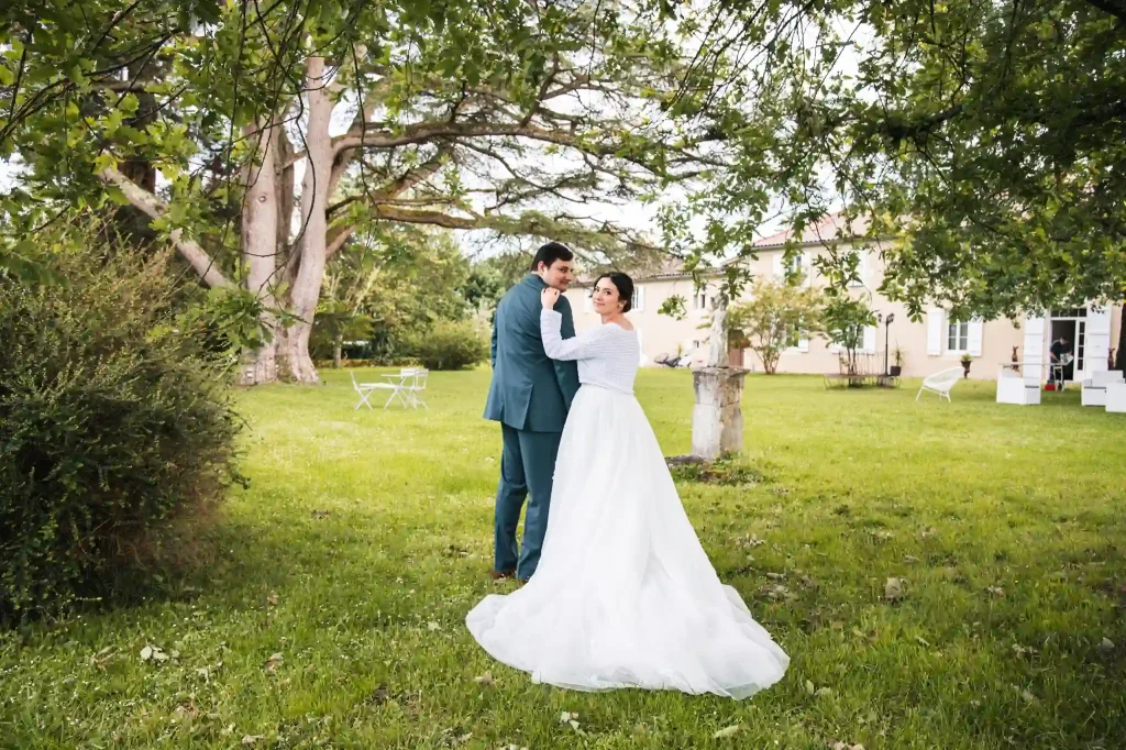 Les mariés marchent bras dessus, bras dessous et se retournent pour regarder leur photographe de mariage à Toulouse qui marche derrière eux.