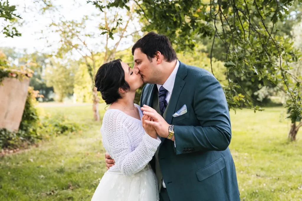 Les mariés s'embrassent en se tenant la main lors de la séance photo de couple pendant leur mariage