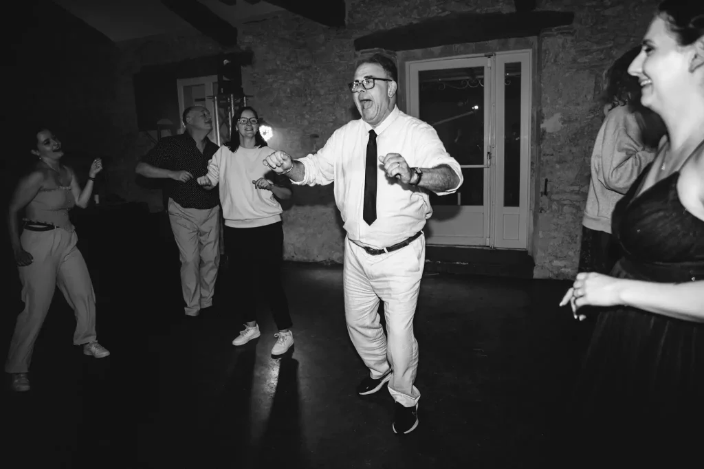 Le père de la marié danse avec toute son âme sur la piste de danse entouré par d'autres invités