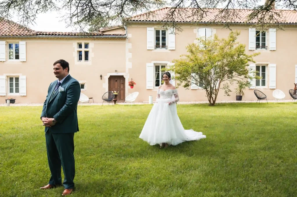 Le photographe de mariage à Toulouse propose une séance first look aux mariés à la Chartreuse de Dane. La marié se rapproche lentement de son mari qui lui tourne le dos.