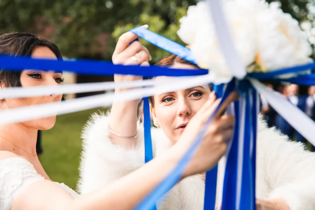 La témoins de la mariée démêle les rubans autour du bouquet de la mariée pour démarrer l'animation pendant le cocktail
